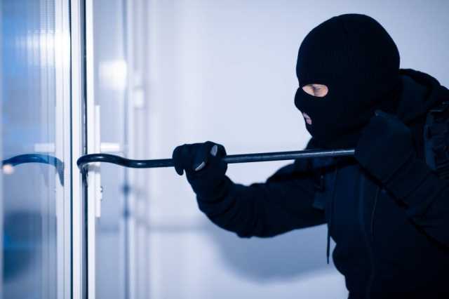 robber-in-black-balaclava-cracking-door-with-crowbar